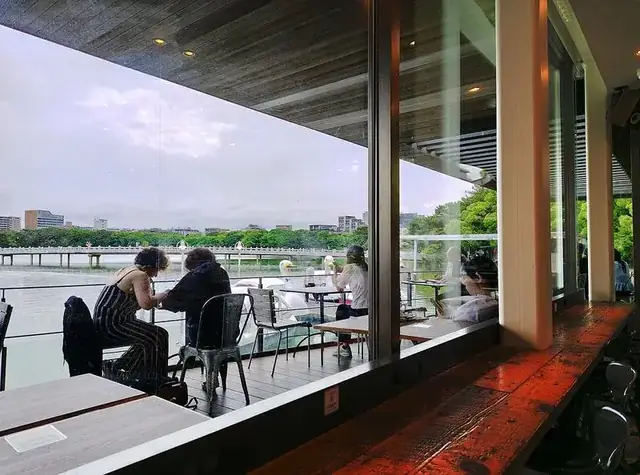 Ilustrasi teras kafe outdoor dengan meja dan kursi — bukan foto lokasi OGI